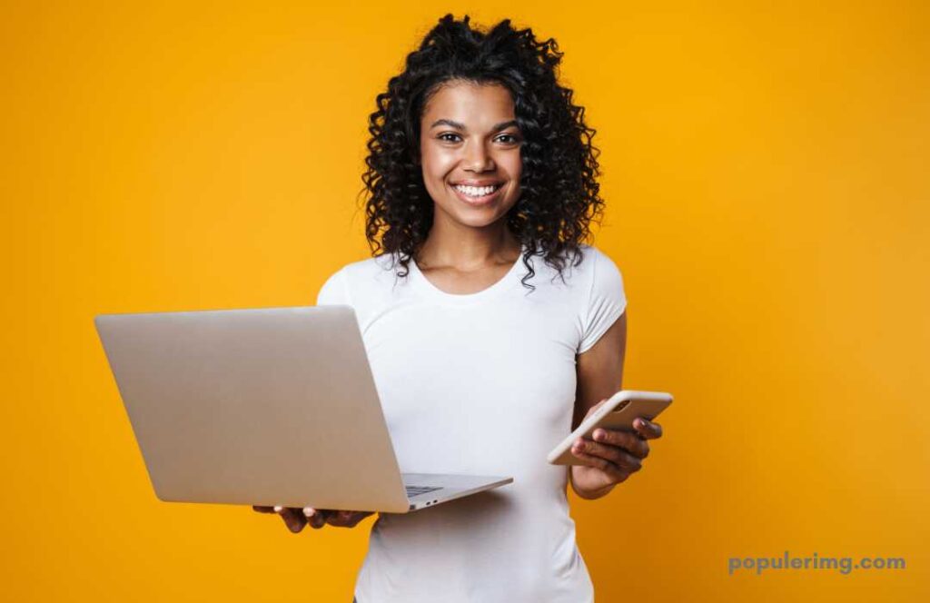 Image Of A Smiling Girl With Laptop And Mobile In Hand 