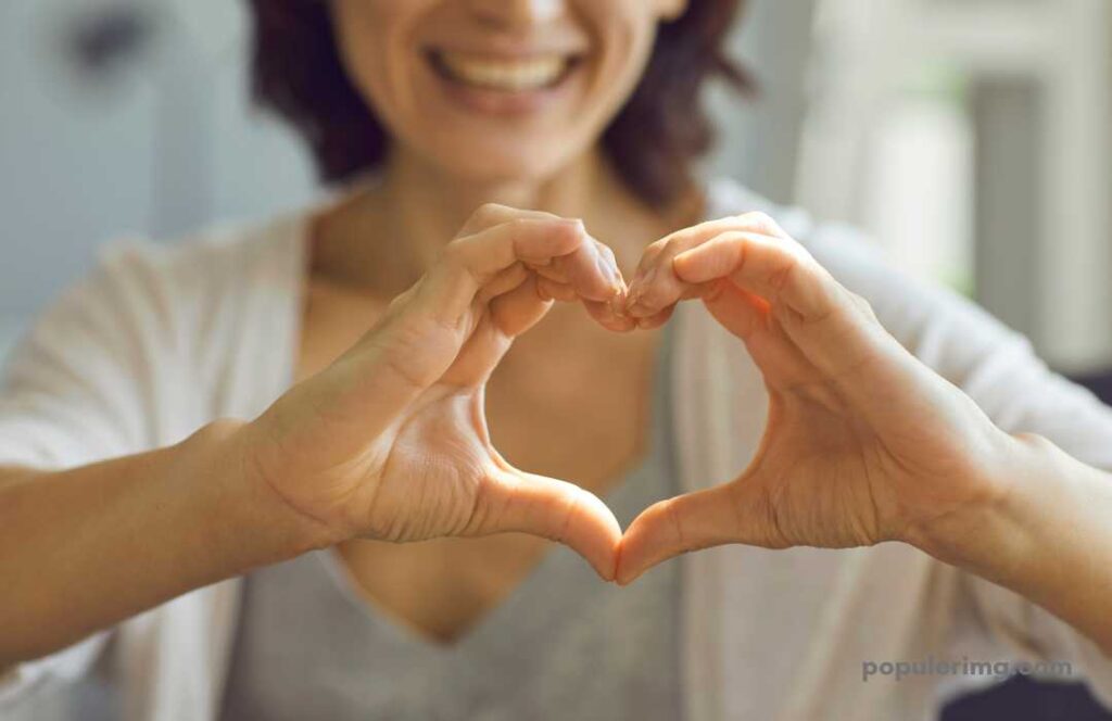 A Woman Smiling Making A Heart With Her Hands 