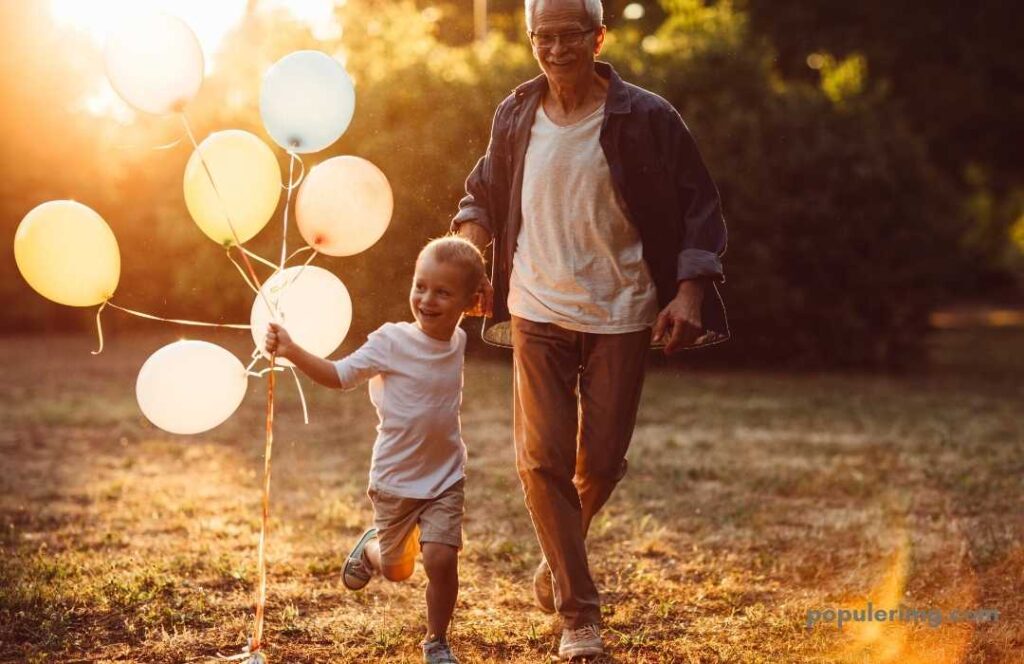 Grandfather And Grandson Running With Balloons In The Garden 