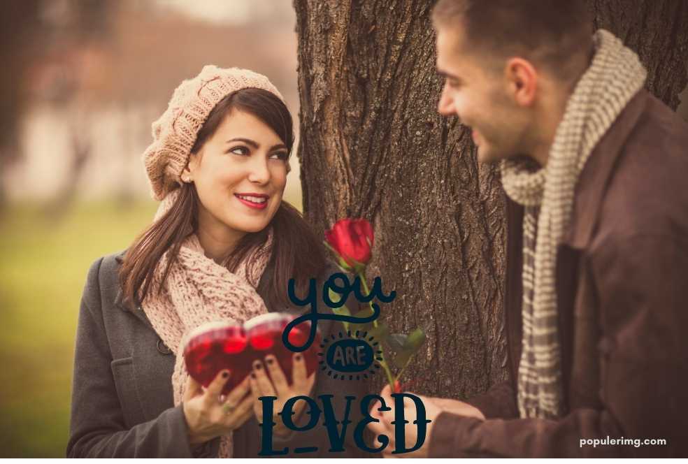 A Man And Woman Standing Next To A Tree With The Words You Are Loved.	