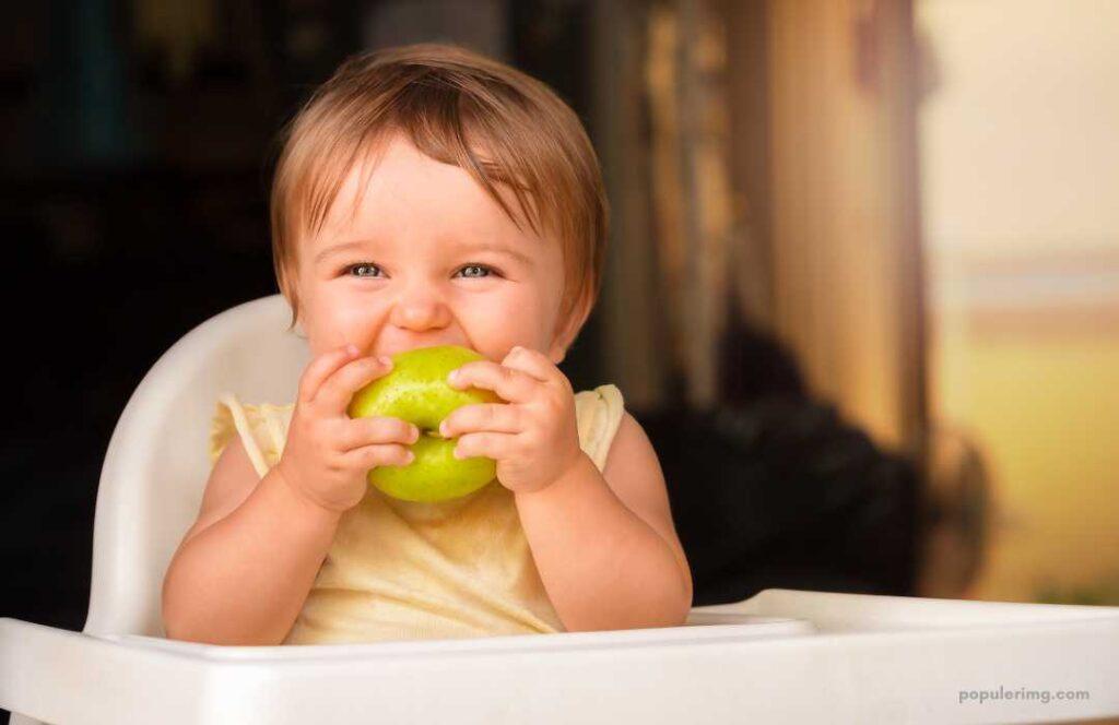 A Baby Eating An Apple In A High Chair