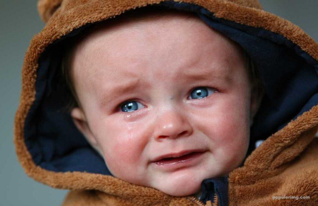 A Baby Is Crying In A Teddy Bear Hoodie.	