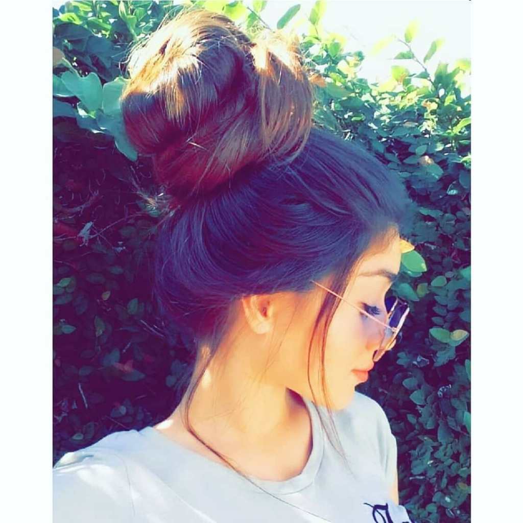 a girl wearing glasses with a bun in her hair.	