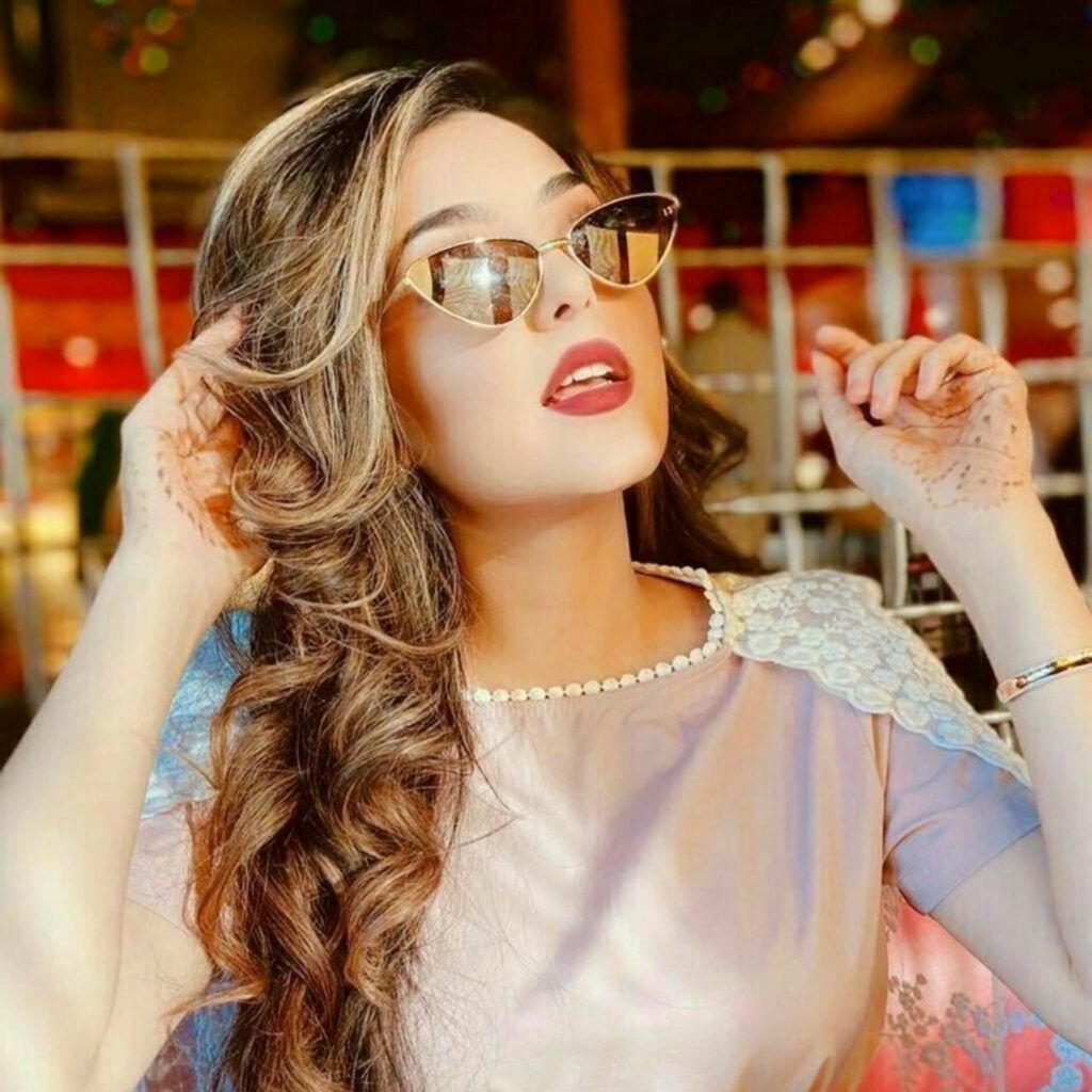 a woman in sunglasses posing in a restaurant.	