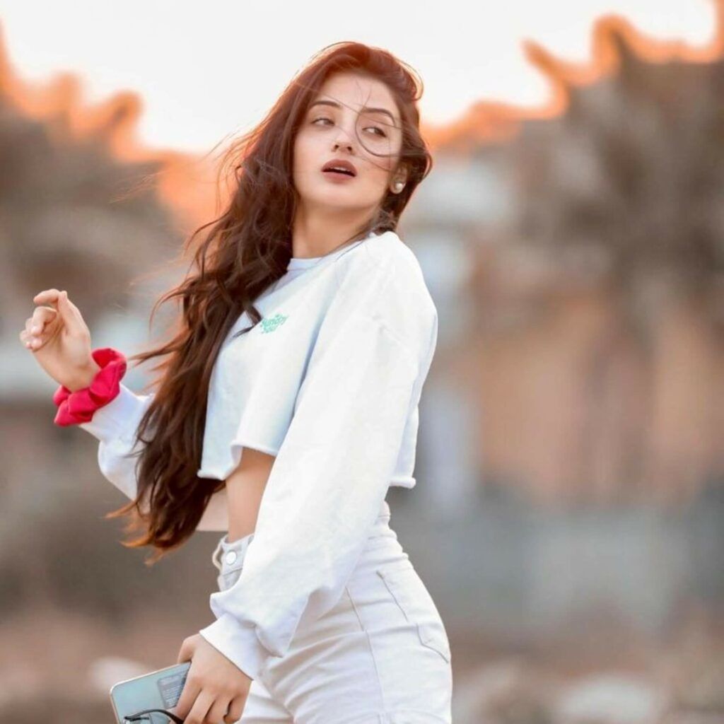 an Indian woman in white crop top and white shorts.	