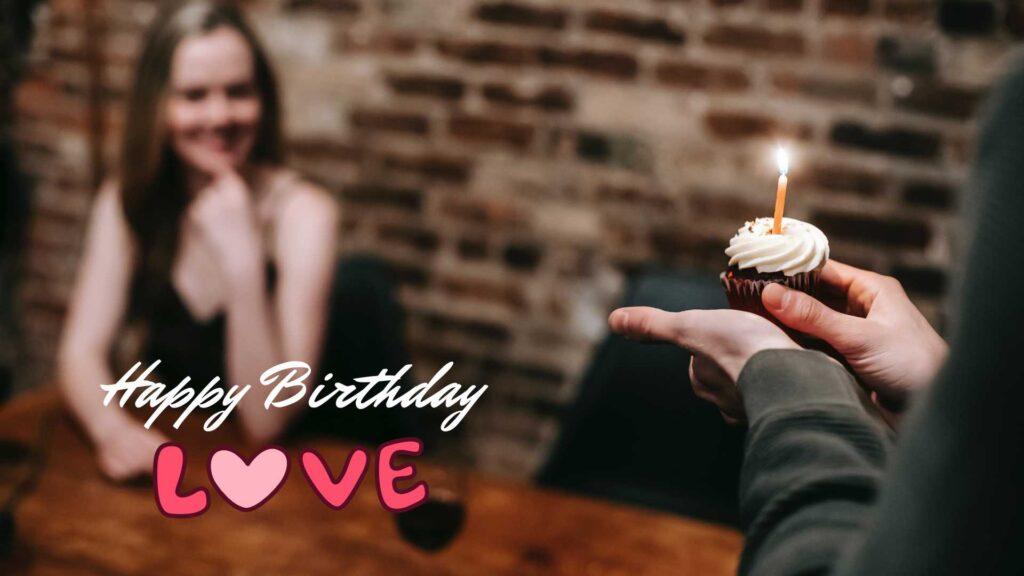 A woman is holding a cupcake with the words happy birthday love.	