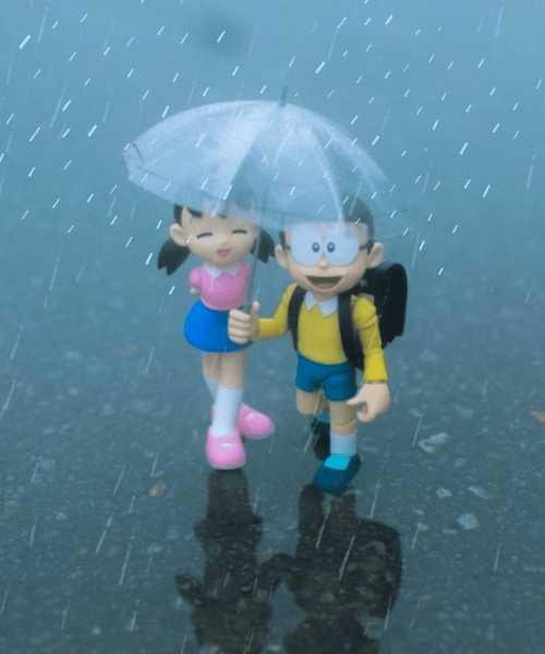 A Toy Couple Holding An Umbrella In The Rain.	